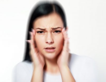 blurred image of a female holding her temples and struggling to see clearly