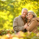 older couple smiling and embracing while outdoors in the Fall
