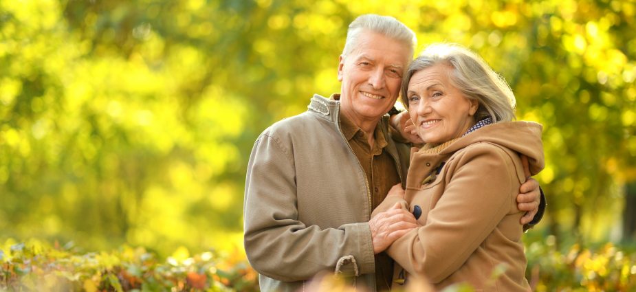 older couple smiling and embracing while outdoors in the Fall