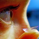 close up of someone placing a contact lens in their right eye