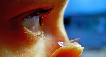 close up of someone placing a contact lens in their right eye