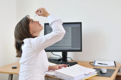 female office worker taking a break from working on her computer to apply eye drops