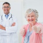 older female vision patient sitting next to her doctor and giving thumbs up