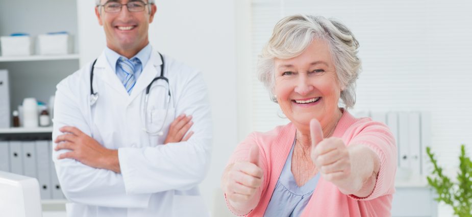 older female vision patient sitting next to her doctor and giving thumbs up