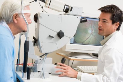 eye doctor using magnification to view the eye of an older male patient