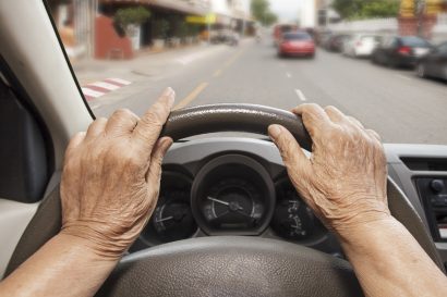 POV of an older, female driver with her hands on the steering wheel staring through the windshield