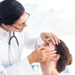 eye doctor performing a hands-on examination of a patient's left eye