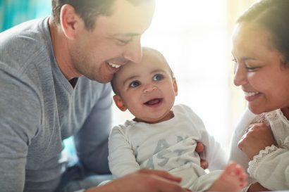 a young couple laughs and plays with their baby boy