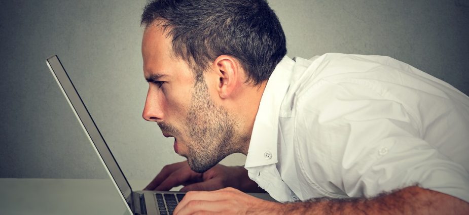 man with his face extremely close to his laptop screen