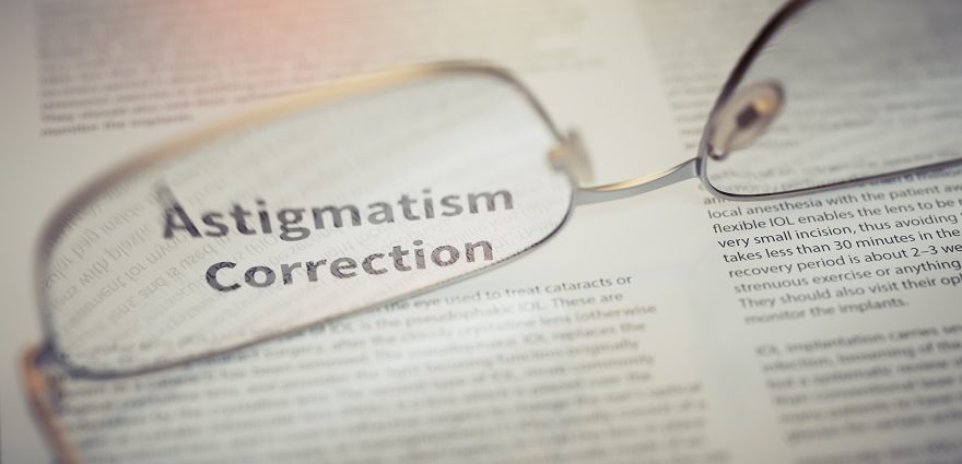 reading glasses sitting on a newspaper and highlighting astigmatism correction