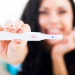 Happy woman holding up a positive pregnancy test