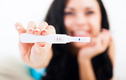 Happy woman holding up a positive pregnancy test