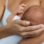 woman cradling her baby's head while breastfeeding