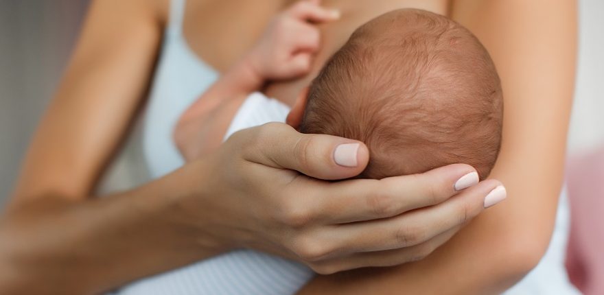 woman cradling her baby's head while breastfeeding